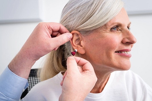 Ältere Frau erhält individuell angepasstes Hörgerät zur Verbesserung des Hörvermögens.